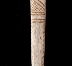 Bone fan guard with incised linear decoration.